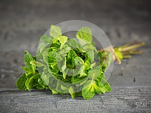 Bunch mint, tied with a rough rope on dark wooden table. The concept of healthy eating.