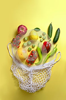 Bunch of mixed organic fruit, vegetables & greens in reusable cotton string net bag.