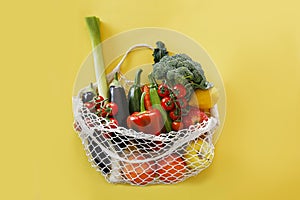 Bunch of mixed organic fruit, vegetables & greens in reusable cotton string net bag.