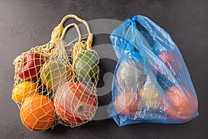 Bunch of mixed organic fruit, vegetables and greens in a string bag and plastic on dark background. Zero waste add