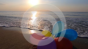 Bunch of multi-colored balloons on the sand sandy beach seashore sea sea waves