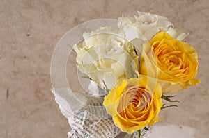 Bunch of multicolor rose flowers wrapped in newspaper over brown