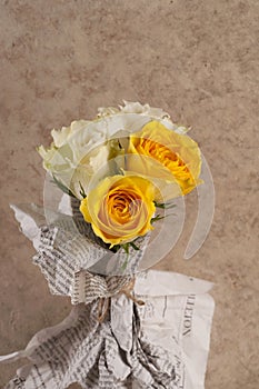 Bunch of multicolor rose flowers wrapped in newspaper over brown