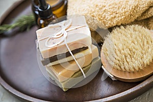 Bunch of natural soaps in wooden plate, natural spa and skincare ingredients with body brush, oil, towel and soaps