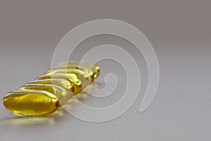 Bunch of omega 3 fish liver oil capsules forming line shaped pattern.