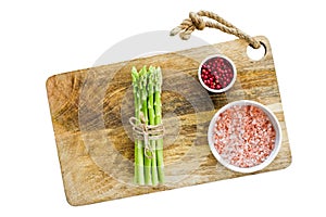 A bunch of organic mini asparagus on a wooden chopping Board. Isolated on white background.