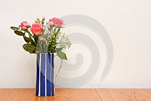 Bunch of pink roses decorate a room with a plain white wall