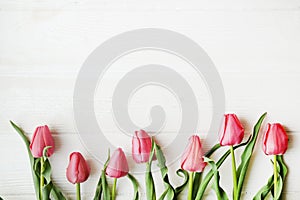 Bunch of pink tulip in beautiful spring holidays composition lying on white wooden textured table background. Mother`s day bouque