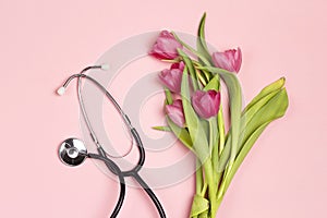 Bunch of pink tulips and stethoscope on pink background. National Doctor`s day