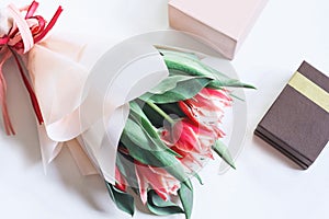 A bunch of pink tulips on white background with a gift box. Spring concept. Greeting card with flowers. Flat lay, top view
