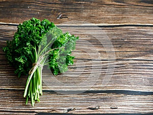 Bunch of raw fresh green curly parsley on wooden background,