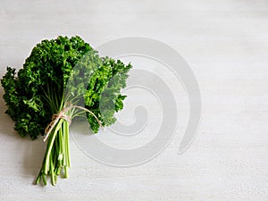 Bunch of raw fresh green parsley on white wooden background, top view with copy space