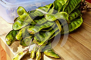 A bunch of raw jengkol vegetables are placed on the table