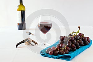 Bunch of red grapes and a glass of red wine with a wine bottle