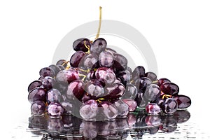 Bunch of red grapes on a white mirror background with reflection and water drops isolated close up