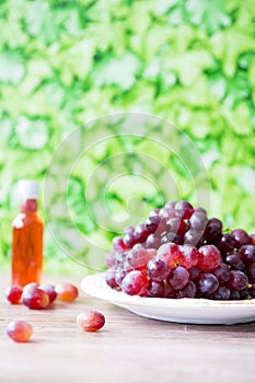 Bunch of red grapes and wine against green blur background