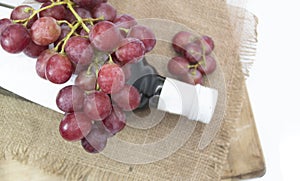 bunch of Red grapes with wine bottle isolated on wooden background