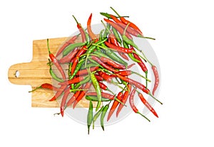 The bunch of red and green fresh chili on a square wooden chopping board isolated on white background.