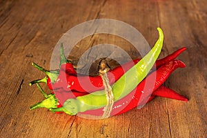 a bunch of red and green hot pepper tied with twine on an old wooden background