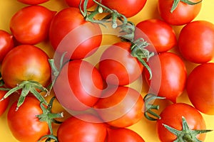 A bunch of red ripe tomatoes lie on a yellow background.