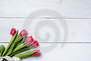 Bunch of red tulips on blue wooden table. Banner mockup card with copy space for congratulation, woman or mother day, easter, spri