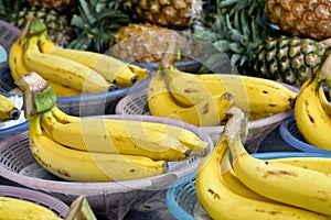 Bunch of ripe Bananas and pinneaples at background in a street market in Bangkok, Thailand. Horizontal