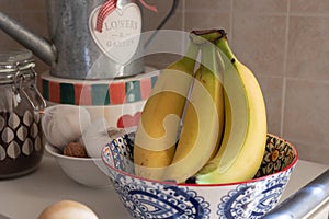 Bunch of Ripe Yellow Bananas inside a Hand Painted Ceramic Pottery Bowl in the Kitchen