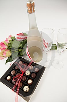 Bunch of roses, champagne bottle, wine glasses and assorted chocolate box