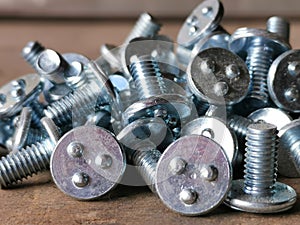 A bunch of round head all thread spot weld bolt screw on wooden table.