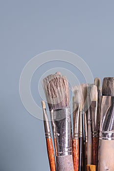 A Bunch of Rustic Artist Brushes Against Blue Background