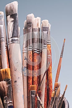 A Bunch of Rustic Artist Brushes Against Blue Background