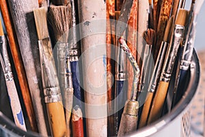 A Bunch of Rustic Artist Brushes in a Metal Bucket