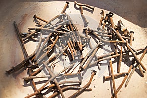 Bunch of Rusty nails in a brown clay plate.