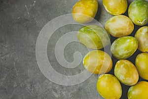 Bunch of scattered ripe juicy yellow and green plums arranged in border on dark stone background.Autumn fall harvest, Thanksgiving