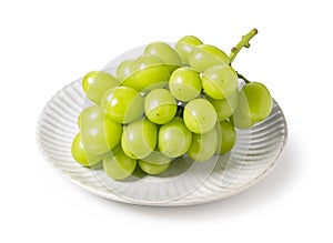 Bunch of Schein Muscat grapes on a plate set against a white background