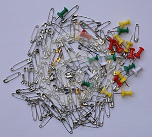 Bunch of shiny silver and gold color safety pins along with colorful push pins