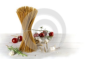 Bunch of standing wholemeal spaghetti on white wood with some to