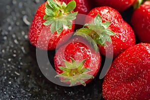 Bunch of strawberries. Wet ripe strawberry on a black background close up. Red berries with water drops. Selective focus