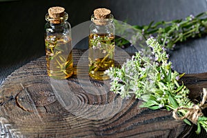 Bunch of thyme, thyme essential oil in glass bottles on dark wooden background with copy pace for your text. Background