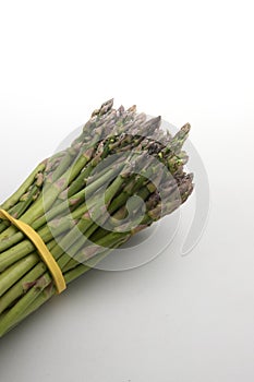 Bunch of tied green asparagus on neutral white background