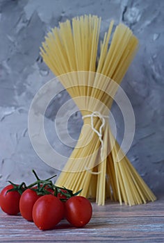 A bunch of tomatoes on the background of a bunch of spaghetti tied with a rope