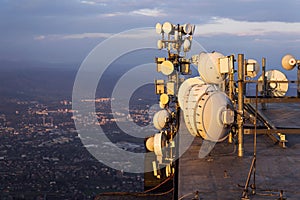 Bunch of transmitters and aerials on the telecommunication tower during sunset