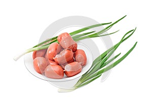 Bunch of uncooked sausages on white dish and green onions