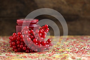 Bunch of viburnum berries, viburnum berry jam in a glass jar on an embroidered tablecloth. Preparations for the winter from a cold