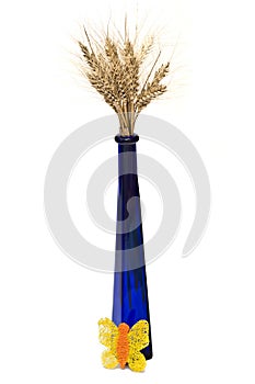 Bunch of wheat spikes in blue vase with decoration