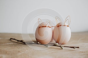Bunch of white eggs with willow branch and bunny ears on wooden background