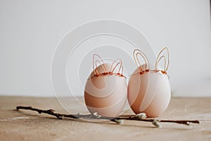 Bunch of white eggs with willow branch and bunny ears on wooden background