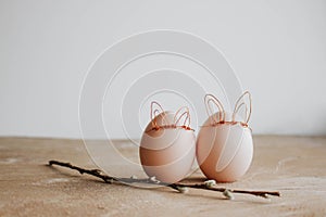 Bunch of white eggs with willow branch and bunny ears on wooden background