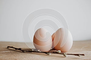 Bunch of white eggs with willow branch on wooden background