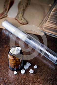 Bunch of white pills with glass ampoules and old medical book